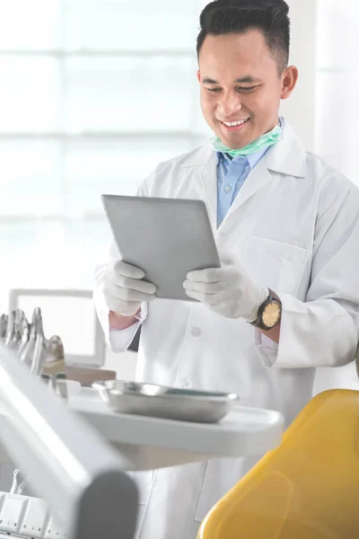 Стоматолог-мужчина в клинике с помощью планшета — стоковое фото