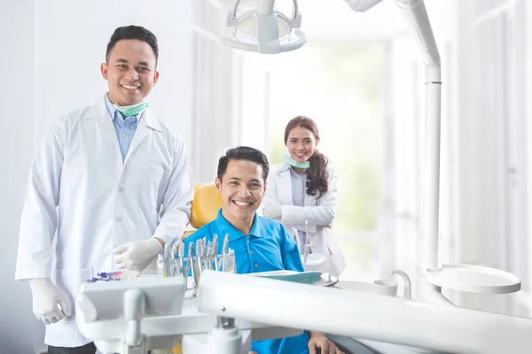 Dentista sorrindo com paciente do sexo masculino na clínica odontológica — Fotografia de Stock