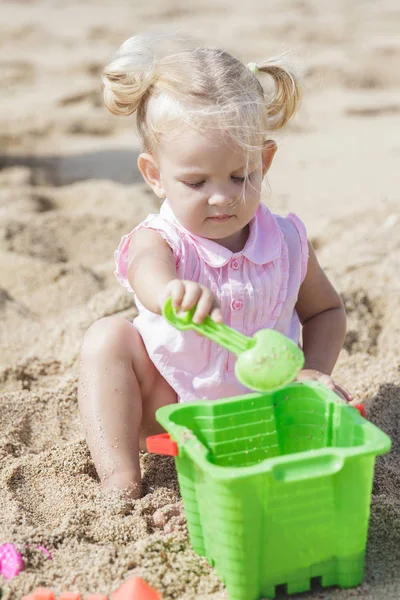 Pequena menina brincando brinquedos de areia na praia — Fotografia de Stock