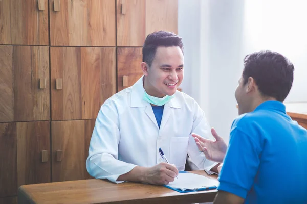 Tandläkare att prata med sin patient vid tandvård kliniken — Stockfoto