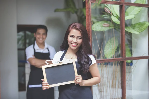 Servitris som står på framsidan av ett café inbjuder människor att komma — Stockfoto