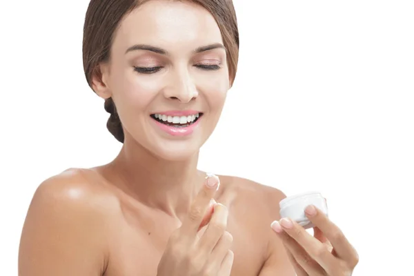 Hermosa mujer sonriendo mientras toma un poco de crema facial — Foto de Stock