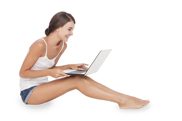 Ung kvinna sitter på golvet medan du arbetar på sin laptop — Stockfoto