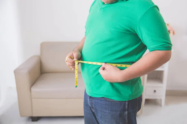 Homem com sobrepeso medindo sua barriga em casa — Fotografia de Stock