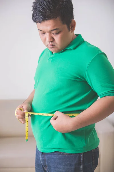 Nadwagą mężczyzna mierzenia jego brzuch w domu — Zdjęcie stockowe