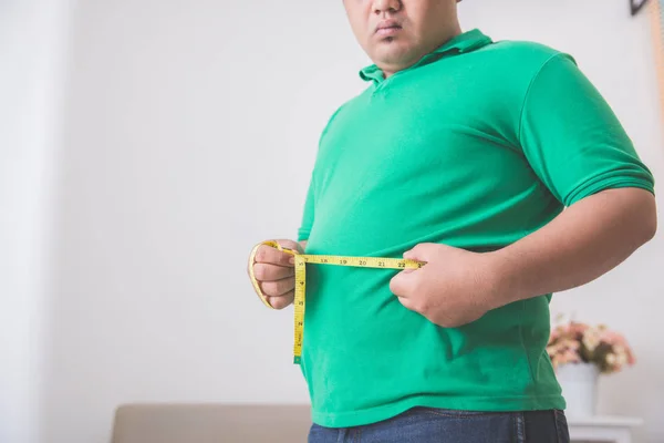 Hombre con sobrepeso midiendo su vientre en casa —  Fotos de Stock