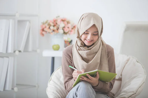 Schöne asiatische Frau mit Kopftuch schreibt etwas — Stockfoto