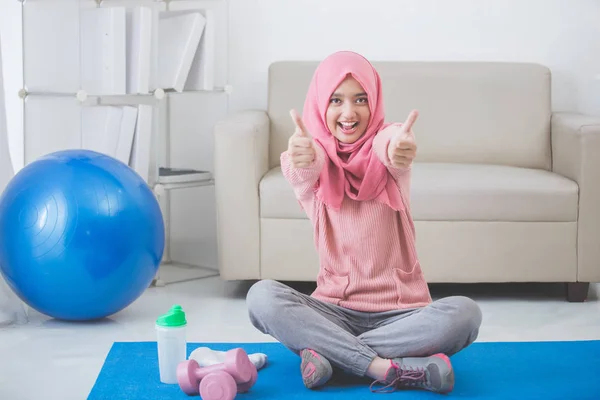 Vrouw met hijab oefening thuis doet. duim omhoog — Stockfoto