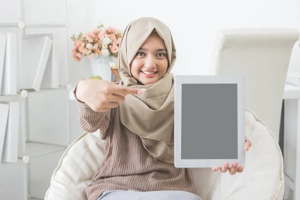 Femme montrant l'écran de la tablette et sourire à la caméra — Photo