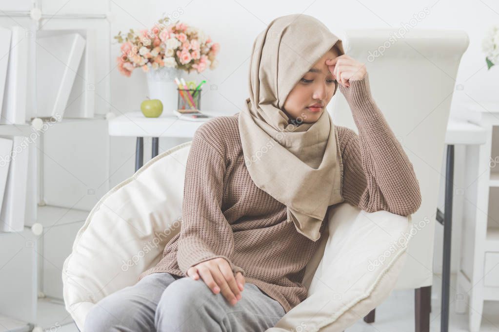 young asian woman hold her head thinking about something 