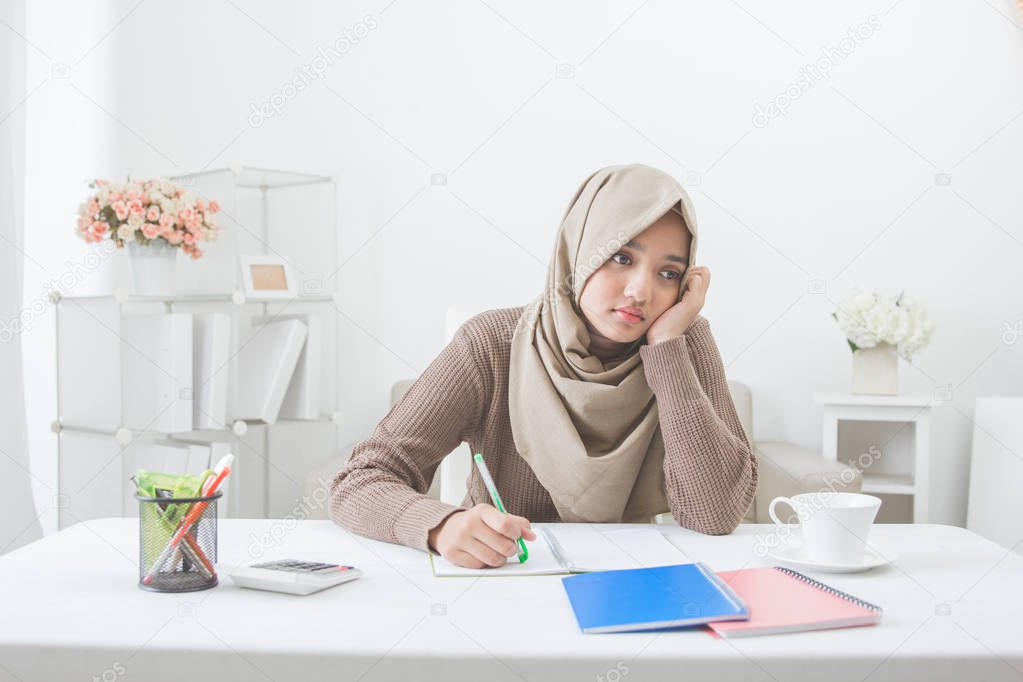 student with hijab tired of doing homework