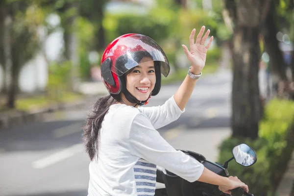 woman riding motorbike and waving hand