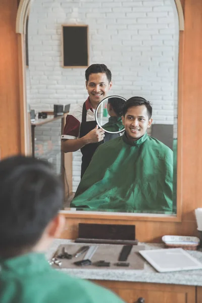 Парикмахер стрижет мужчину в парикмахерской — стоковое фото