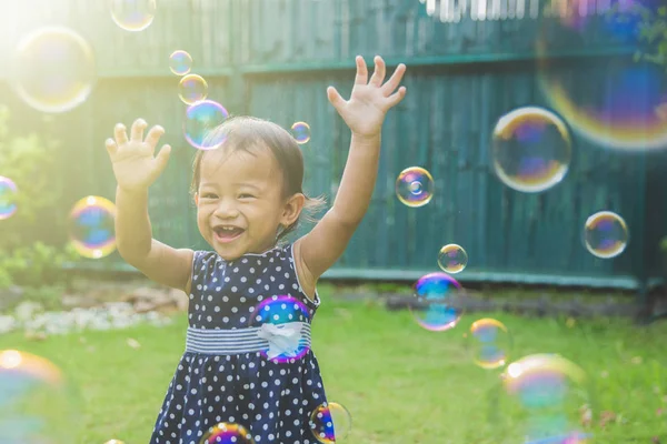 Niña tratando de coger burbujas de jabón —  Fotos de Stock