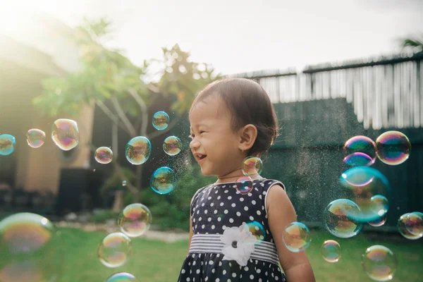 Маленька дівчинка намагається зловити мильні бульбашки — стокове фото