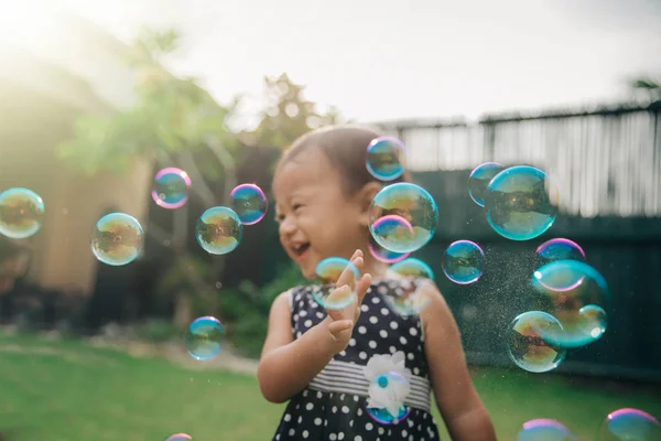 Niña tratando de coger burbujas de jabón — Foto de Stock
