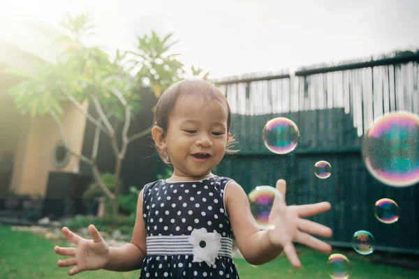 Malá holka snaží chytit mýdlové bubliny — Stock fotografie