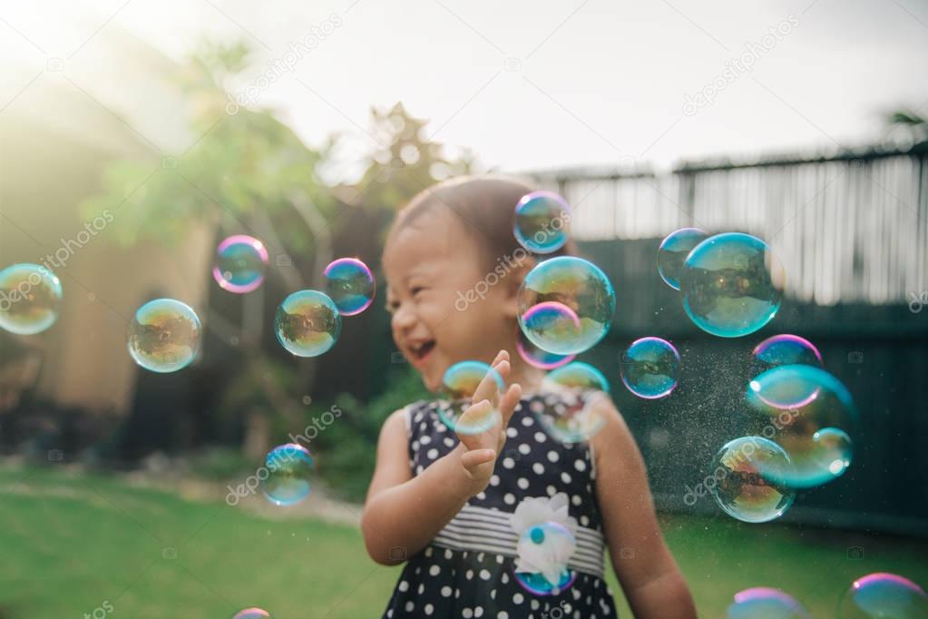 little girl trying to catch soap bubbles