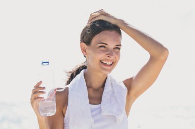 bir şişe maden suyu yenileme için tutan mutlu sportif kadın