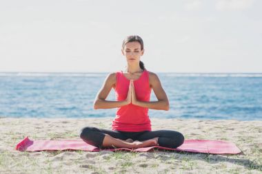 Sportif genç kadının kumsalda Yoga meditasyon yapması