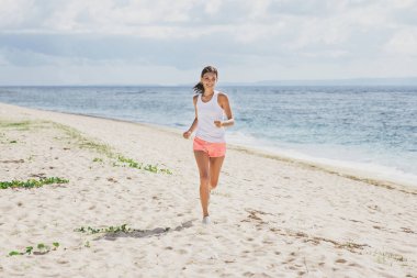 Sportif kadın gökyüzü ve deniz, arka plan ile koşu