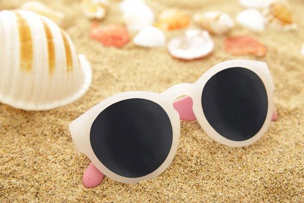 Sunglasses, seashells on the sand — Stock Photo, Image