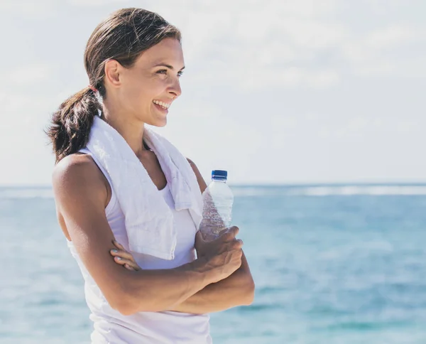 Sporty girl smiling while holding a bottle of mineral water — Stock Photo, Image