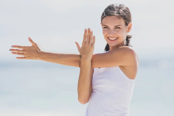 Sportig kvinna leende medan du gör armar som sträcker sig — Stockfoto