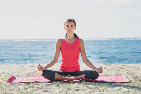 sporty young woman doing yoga meditation at the beach