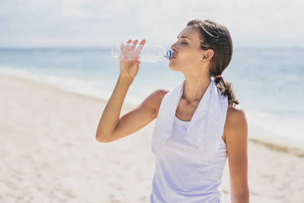 Спортивная женщина пьет минеральную воду после тренировки — стоковое фото