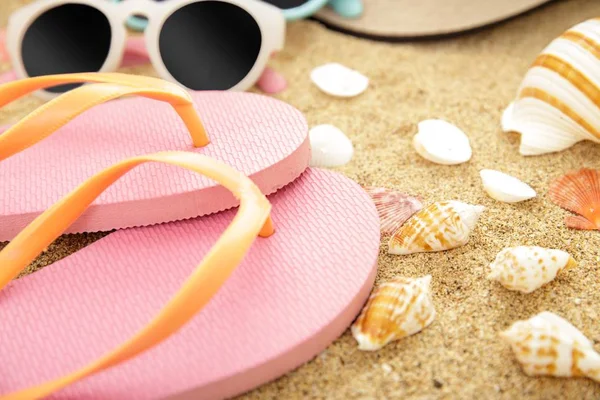 Chinelos cor-de-rosa, óculos de sol e conchas nas areias da praia — Fotografia de Stock