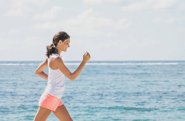 Sportowy kobieta jogging z nieba i morza w tle — Zdjęcie stockowe