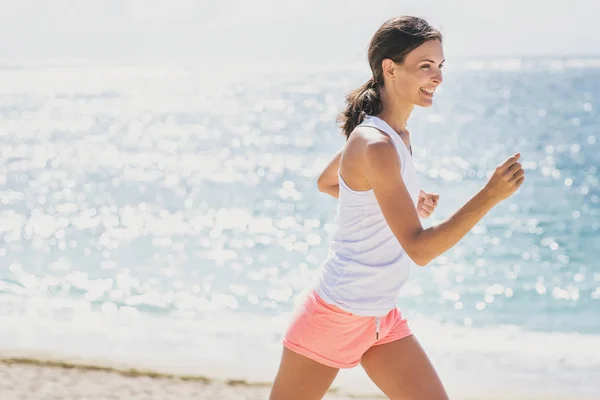 Sportig kvinna jogging med himmel och hav i bakgrunden — Stockfoto