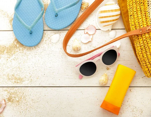 Tongs bleues, crème solaire et lunettes de soleil sur table en bois blanc — Photo