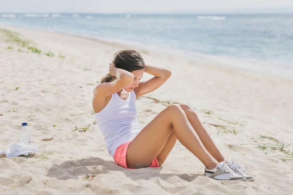 Mujer deportiva haciendo sentarse en la playa — Foto de Stock