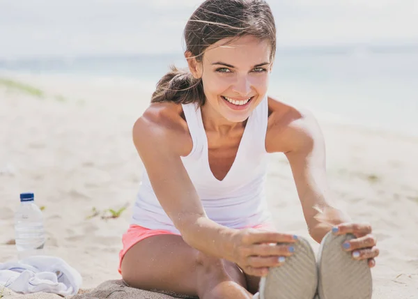 Mujer sana sonriendo mientras hace estiramiento de la pierna —  Fotos de Stock