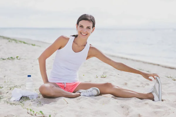 Happy healthy woman smiling while doing leg stretching — Stock Photo, Image
