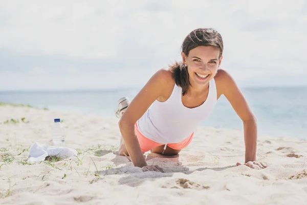 Heureuse femme en bonne santé faisant pousser vers le haut à la plage — Photo