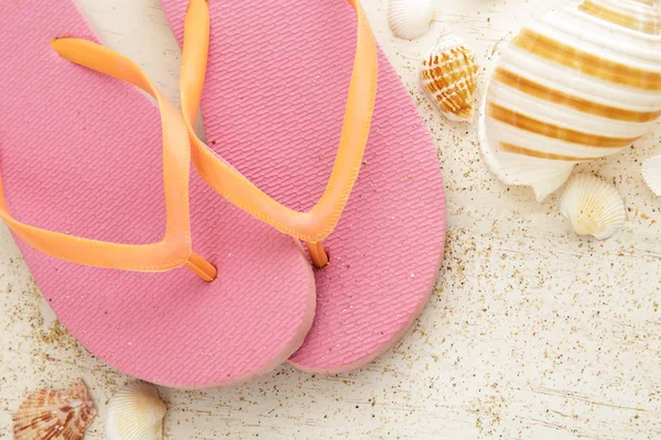 Chinelos rosa com conchas na tábua de madeira branca — Fotografia de Stock