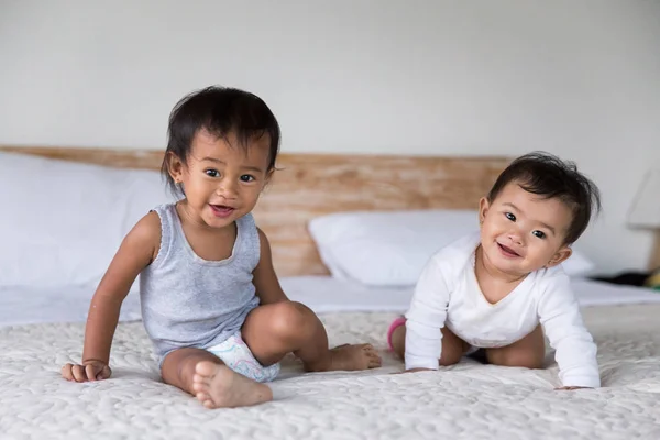 Två söta baby sitter på sängen — Stockfoto
