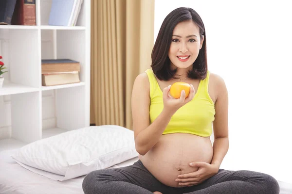 Mulher grávida segurando laranja — Fotografia de Stock