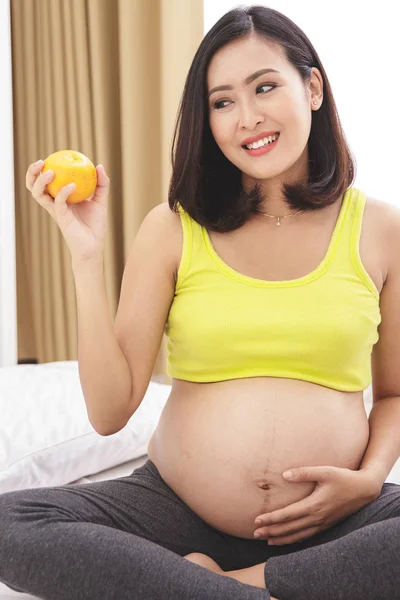 Mujer embarazada sosteniendo naranja — Foto de Stock