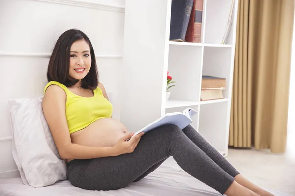 Happy pregnant woman sitting on bed — Stock Photo, Image