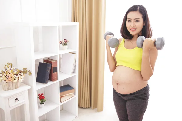 Pregnant woman exercising with dumbbells — Stock Photo, Image