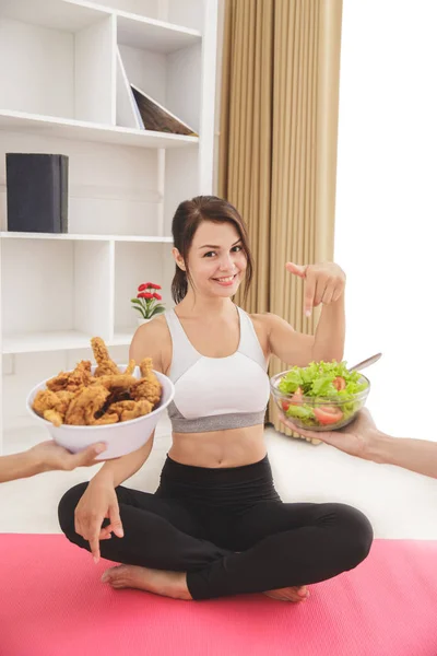 Beautiful sporty woman choosing a bowl of salad than fried chick — Stock Photo, Image