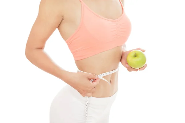 Sporty woman measures her waist with measuring tape while holdin — Stock Photo, Image