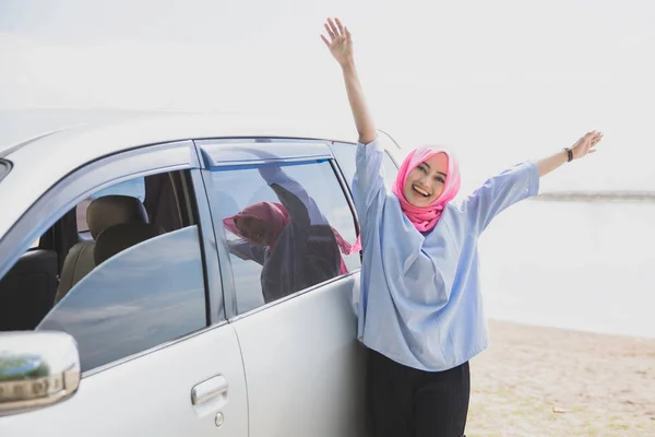 Счастливая женщина, стоящая возле машины на пляже — стоковое фото