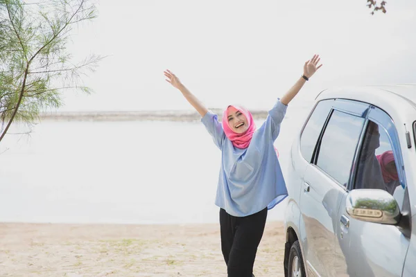 Mujer feliz de pie cerca de coche en la playa — Foto de Stock