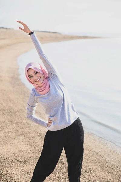 Schöne Frau trägt Hijab beim Dehnen des Körpers am Strand — Stockfoto