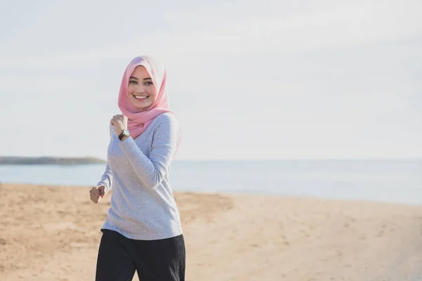 ジョギングしながら笑みを浮かべてヒジャーブを身に着けているスポーティな女性 — ストック写真